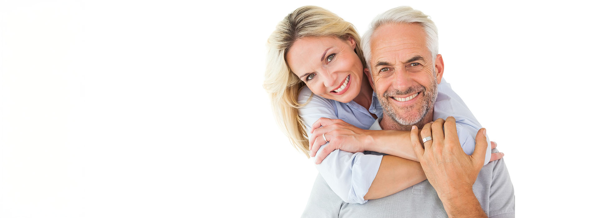 The image shows a man and woman embracing each other with smiles on their faces, both wearing casual clothing they appear to be in a happy and affectionate moment.