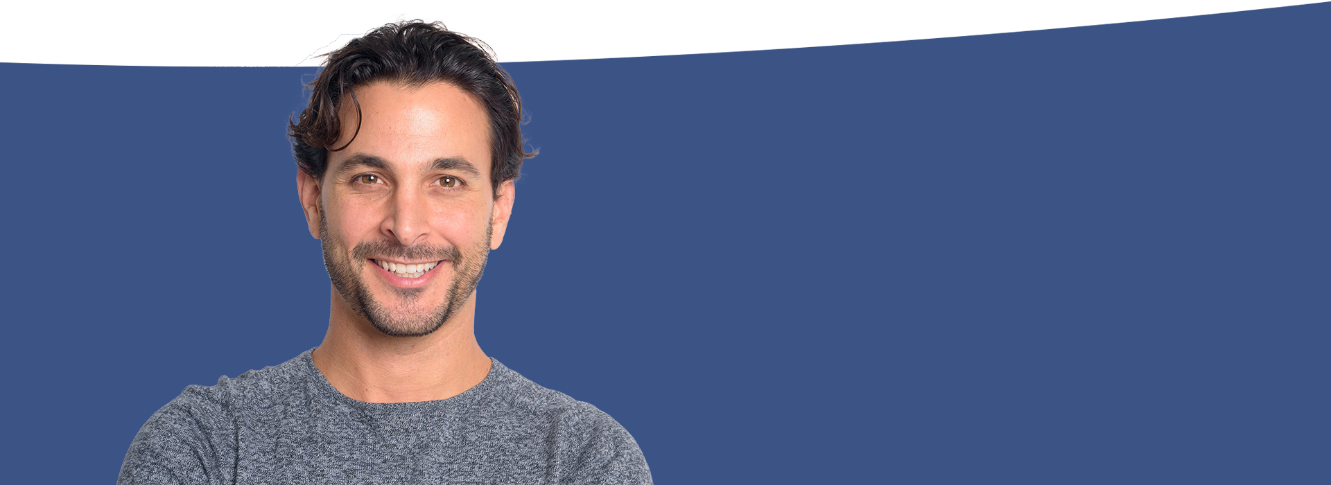 The image features a man with facial hair smiling at the camera, set against a blue background with a partial view of a person on the right side.